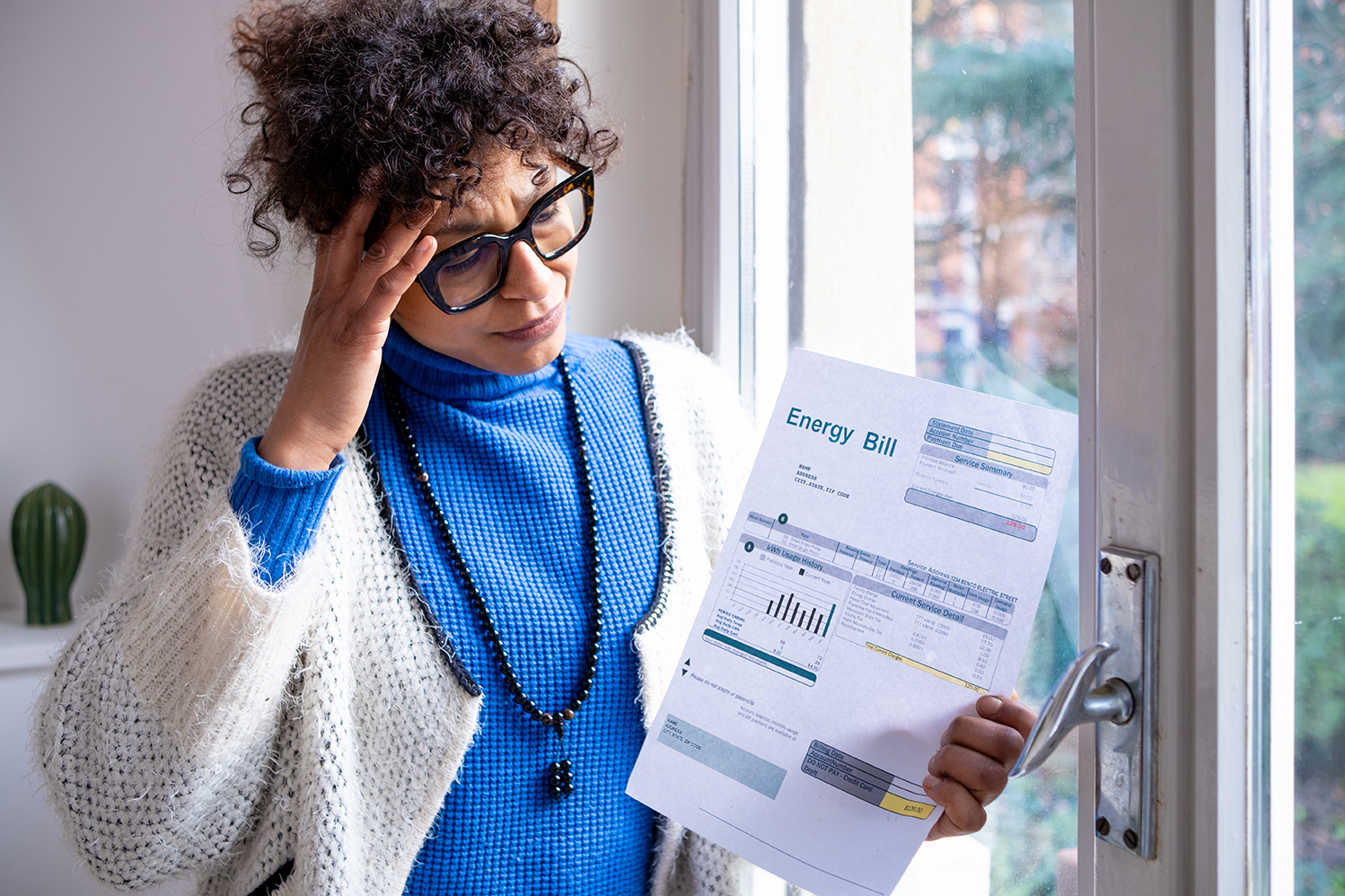 Woman holding utility bill looking stressed
