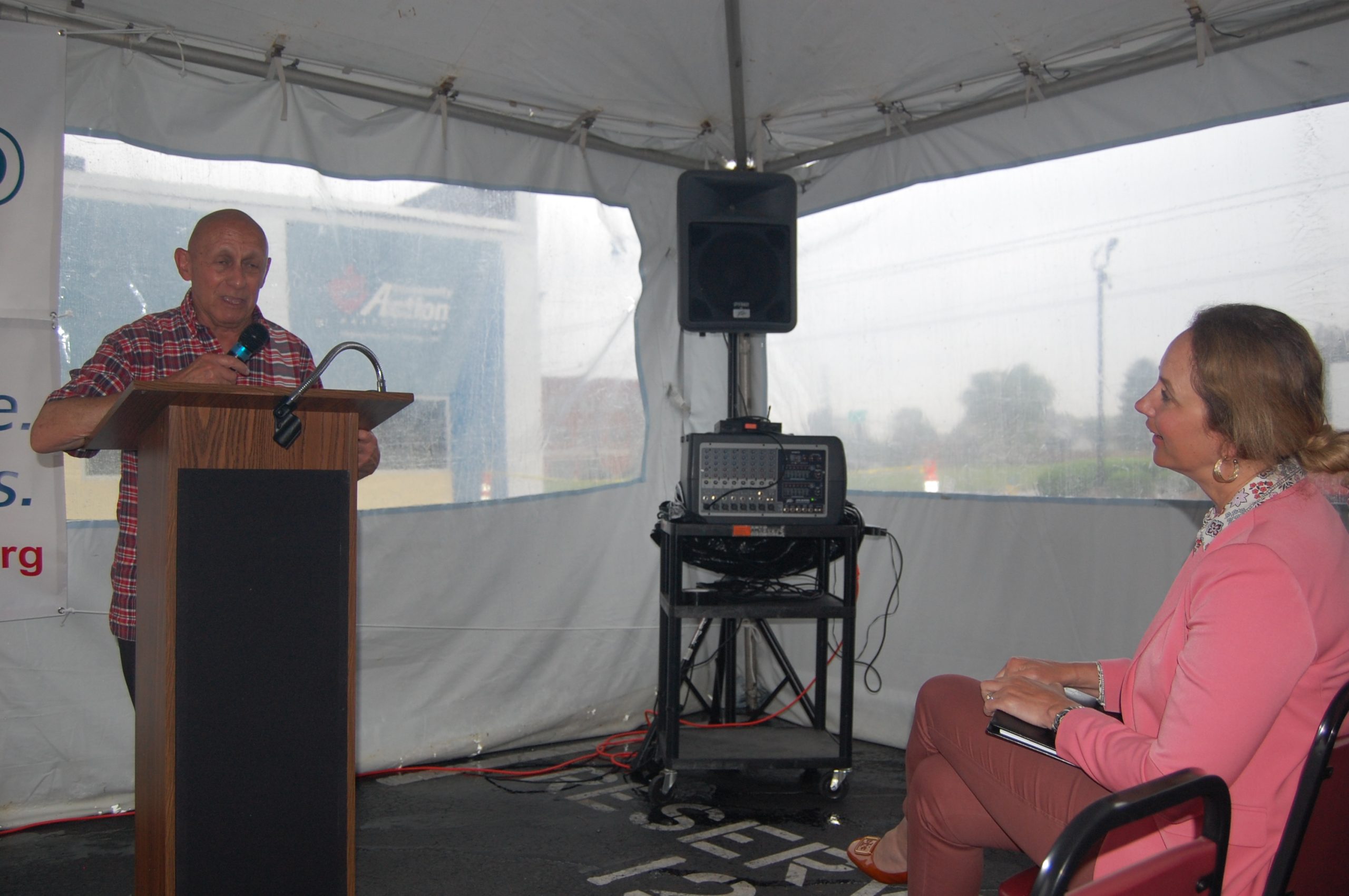 Man speaking at podium in front of public official