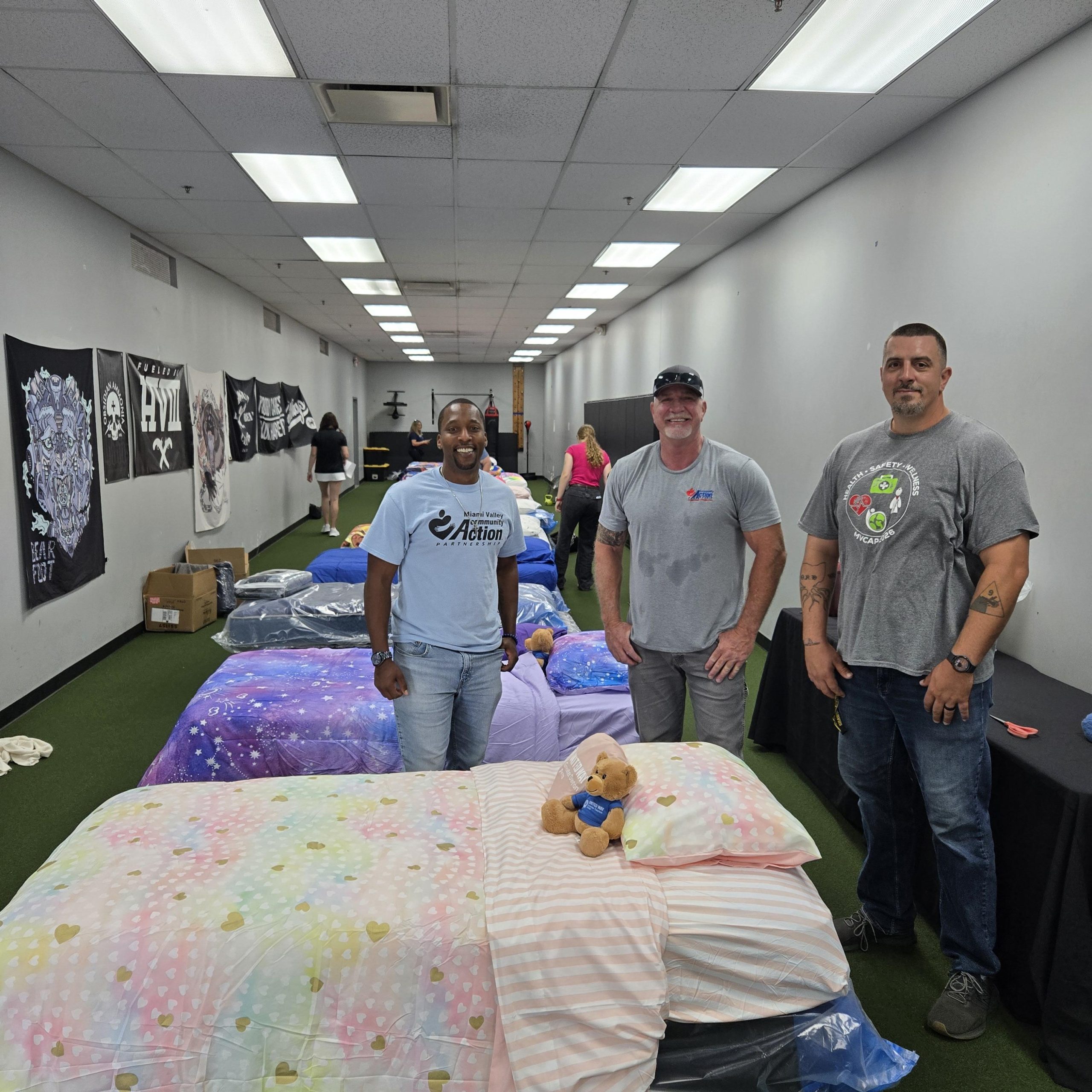 Group of men standing by a line of beds being given away